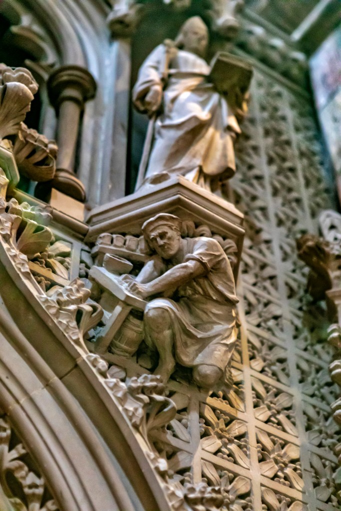The frieze on a cathedral in Scotland shows a priestly figure standing on a platform that rests on the back of a worker below. "Social hierarchy" by schoeband is licensed under CC BY-NC-ND 2.0